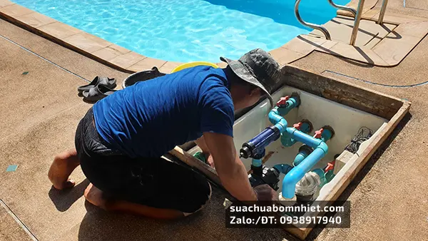 Nhân viên làm việc với các ống bơm nhiệt của hồ bơi sau khi lắp đặt